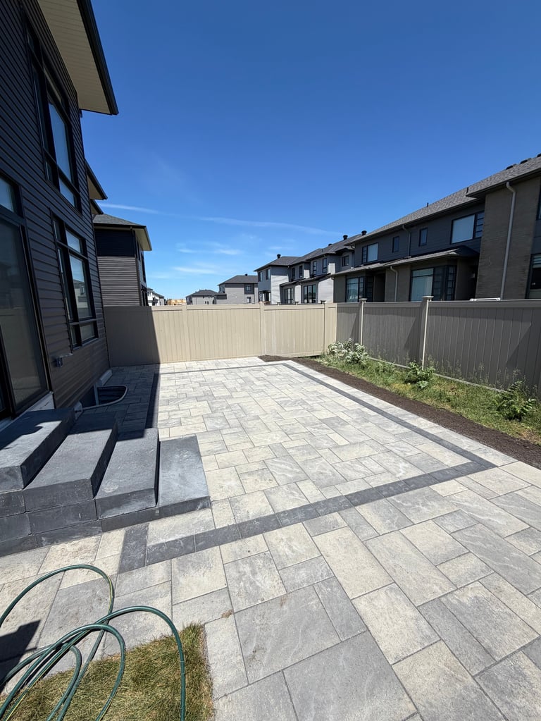 Modern townhouse patio with paved tiles, metal fence, and clear blue sky