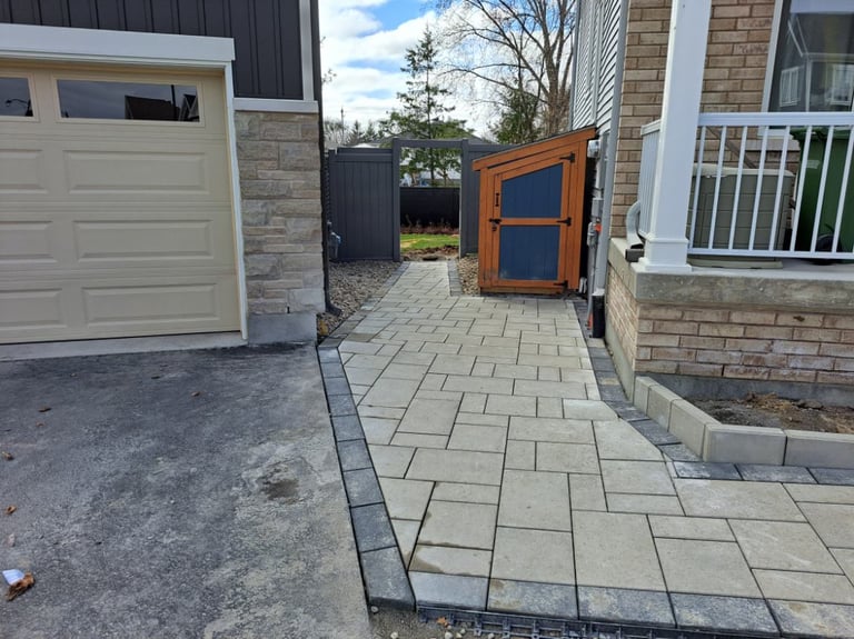 Paved residential driveway with wooden gate, beige garage door, and brick house exterior