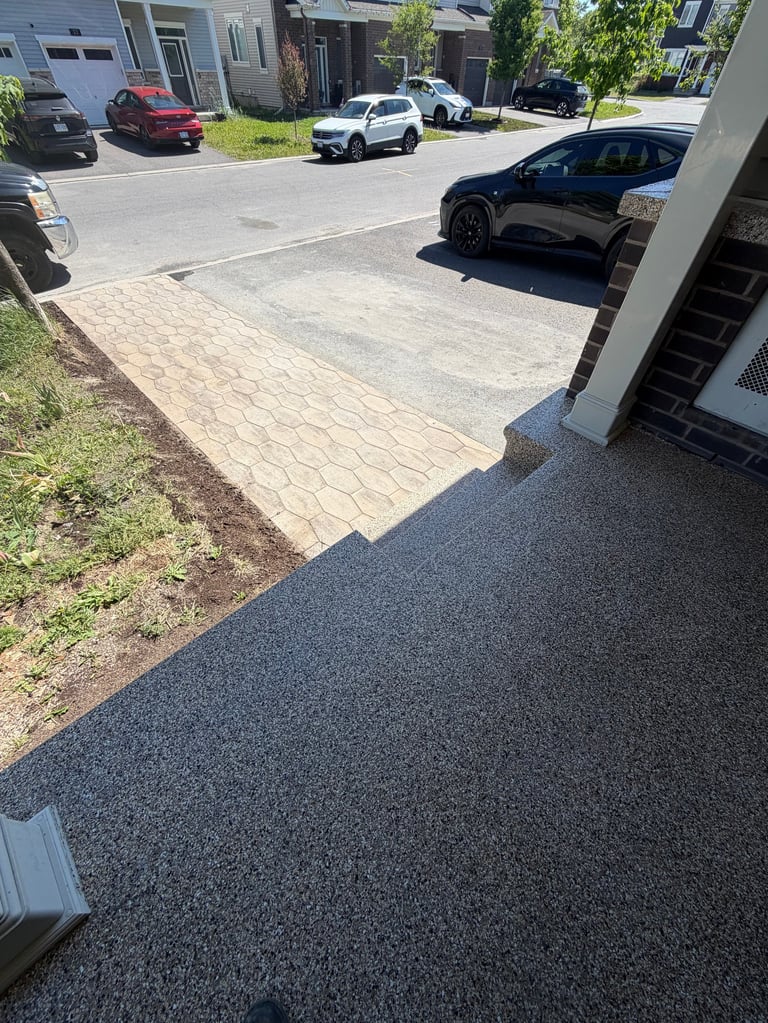 A residential driveway with paver and asphalt surfaces, multiple parked cars visible on a sunny day